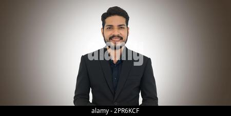 Portrait d'un jeune homme d'affaires avec moustache et barbe en costume noir sur fond marron foncé avec effet d'éclairage. Photo en studio Banque D'Images