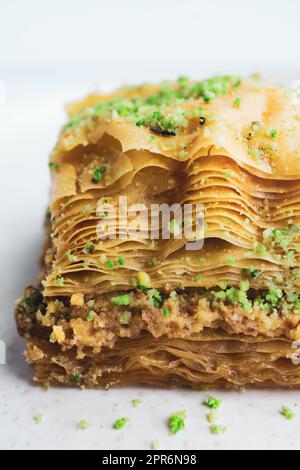 Gros plan sur le dessert de pâtisserie pistache baklava phyllo montrant des couches détaillées et des morceaux de pistache sur fond blanc. Banque D'Images