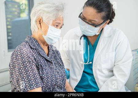 Un médecin asiatique portant un écran facial et un EPI suit une nouvelle norme pour vérifier la sécurité du patient protéger infection Covid 19 coronavirus éclosion à l'hôpital de soins infirmiers de quarantaine. Banque D'Images