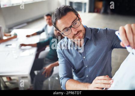 Le processus créatif. Photo d'un homme mûr écrivant sur un tableau blanc tout en donnant une présentation à des collègues dans un bureau. Banque D'Images