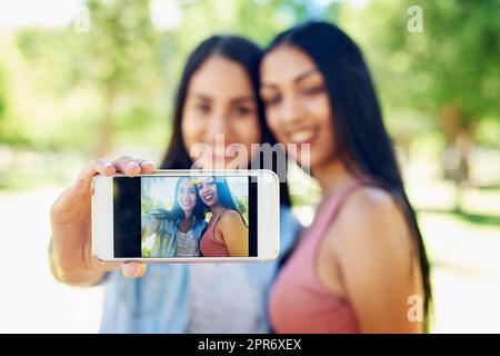 Les meilleurs amis prennent les meilleurs selfies. Photo de deux jeunes amis qui prennent un selfie ensemble en plein air. Banque D'Images