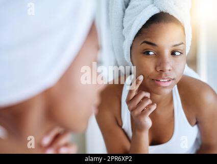 Sa nouvelle routine de soin de la peau montre des résultats. Photo d'une jeune femme inspectant sa peau devant le miroir de la salle de bains. Banque D'Images