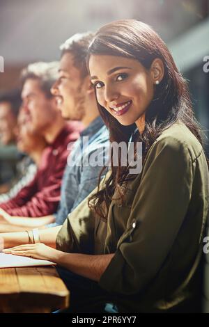 Créez votre propre succès. Portrait d'un jeune designer assis dans une réunion avec ses collègues en arrière-plan. Banque D'Images