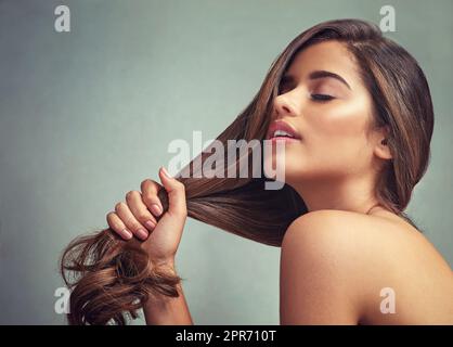 Aimez-vous, aimez vos cheveux. Studio photo d'une belle femme avec de longues serrures posant sur un fond gris. Banque D'Images