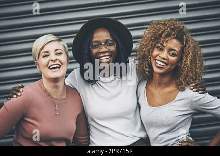 Nous avons tellement de chance de nous avoir les uns les autres. Photo d'un groupe diversifié d'amis féminins s'embrassant les uns les autres à l'extérieur. Banque D'Images