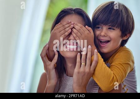 Le temps de jeu établit un lien sain entre les enfants et leurs mères. Photo d'un adorable petit garçon qui couvre les yeux de sa mère à la maison. Banque D'Images