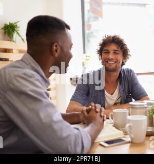 Dude, alors comment allez-vous. Deux jeunes hommes ayant une conversation tout en prenant un café dans un café. Banque D'Images