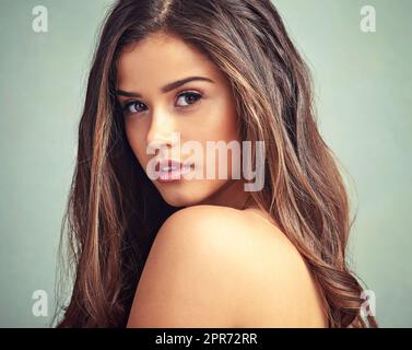 La beauté est fraîche et parfaitement naturelle. Studio portrait d'une belle femme avec de longues serrures posant sur un fond gris. Banque D'Images