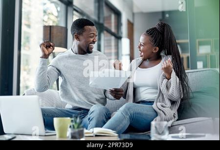 Rien ne se sent mieux que d'être sans dette. Photo d'un jeune couple célébrant tout en passant par la paperasse à la maison. Banque D'Images