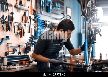 Les bicyclettes sont son entreprise. Photo d'un homme travaillant dans un atelier de réparation de vélos. Banque D'Images