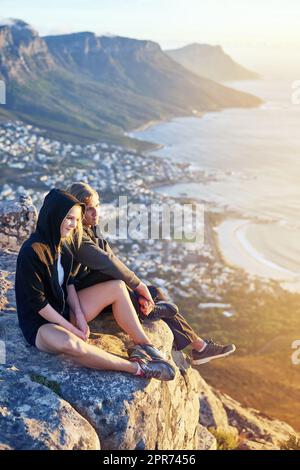 Vue d'en haut. Photo en longueur d'un jeune couple assis sur un sommet de montagne. Banque D'Images