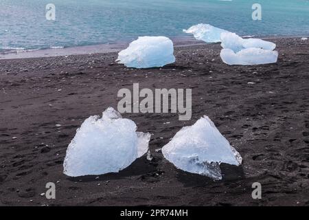 Diamond Beach en Islande avec des icebergs bleus qui fondent sur le sable noir et la glace qui gante avec la lumière du soleil. Banque D'Images