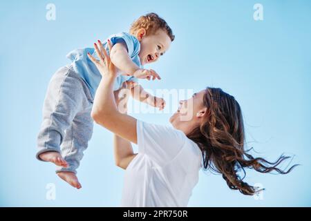 Elle a promis du soulever à droite. Photo courte d'une jeune femme attirante et de son adorable bébé garçon jouant à l'extérieur. Banque D'Images