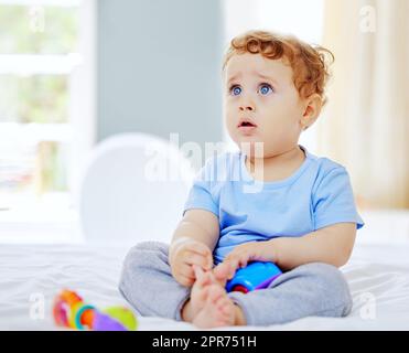 Quelqu'un jouera avec moi. Photo en longueur d'un adorable petit garçon jouant dans la chambre de ses parents à la maison. Banque D'Images