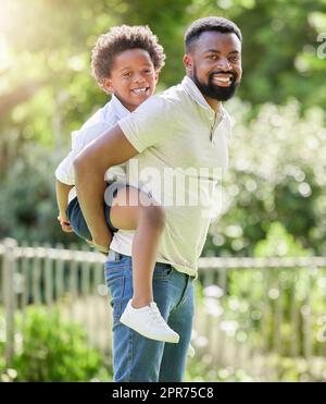 Je veux juste lui donner le meilleur. Portrait d'un père qui donne à son fils une promenade de pigeyback à l'extérieur. Banque D'Images