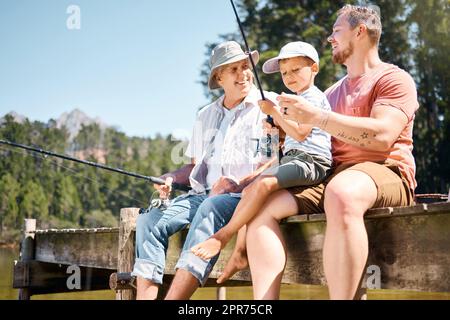 Les garçons voulaient passer du temps de qualité ensemble. Photo d'un petit garçon pêchant avec son père et son grand-père à un lac dans une forêt. Banque D'Images