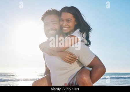 Collage sur la plage. Portrait court d'un beau jeune homme qui soutient sa femme sur la plage. Banque D'Images