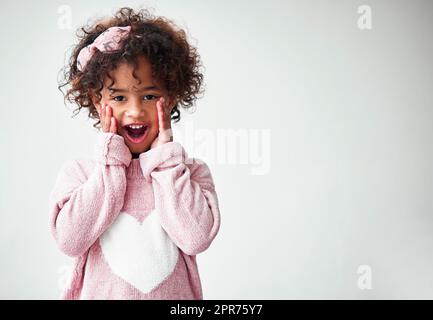 Oh mon Dieu. Photo d'une adorable petite fille à la recherche surprise sur fond gris. Banque D'Images