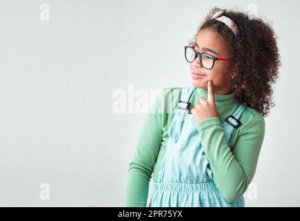 Comme stardust, qui écoute les ailes des fées. Photo d'une petite fille portant des lunettes sur un fond gris. Banque D'Images