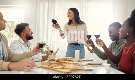 À mes amis qui restent à mes côtés par le bon et le mauvais. Photo d'un groupe de personnes partageant un toast autour de la table à manger dans une maison. Banque D'Images