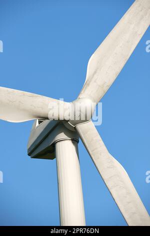 Une éolienne et des pales de rotor isolées contre un ciel bleu sur une ferme durable et écologique. Vue à angle bas de la récolte d'une source d'énergie biodégradable pour produire de l'électricité à partir de climats venteux Banque D'Images