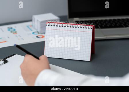 Ordinateur portable spirale vierge ouvert avec Une calculatrice et une femme d'affaires tenant Un stylo. Bloc-notes et crayon à lignes vides sur le dessus D'Un bureau avec Un dispositif de calcul. Banque D'Images