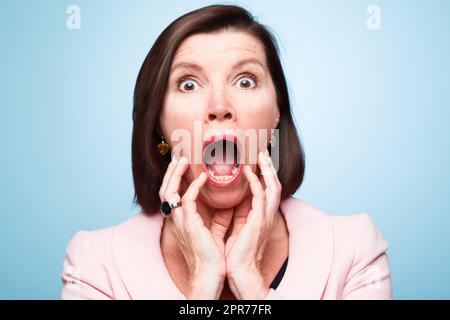 Quelle surprise. Photo d'une femme mûre qui a l'air choquée par rapport à un arrière-plan de studio. Banque D'Images