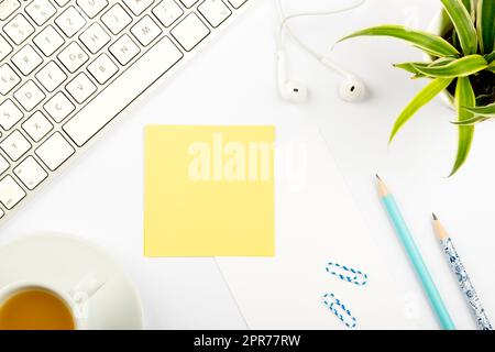 Annonces importantes sur des morceaux de papier sur le bureau avec fleur, casque, stylo, trombones, boisson chaude et clavier. Idées de base sur la note sur la table avec crayon et thé. Banque D'Images