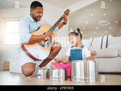 La famille connaît vos défauts mais vous aime, de toute façon. Photo d'un père et d'une fille jouant de la musique à la maison. Banque D'Images