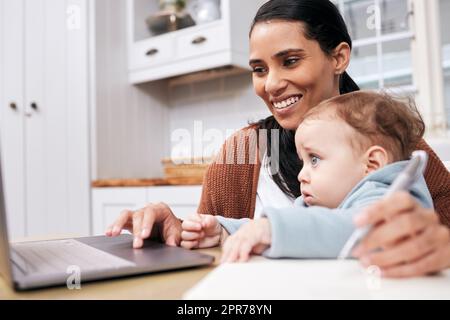 Les mamans courent le monde. Prise de vue d'une jeune femme qui passe par la paperasse tout en tenant son fils à la maison. Banque D'Images