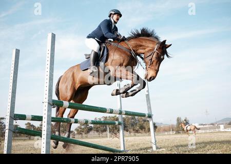 Et plus. Prise de vue en longueur d'une jeune femme qui saute sur un obstacle sur son cheval. Banque D'Images