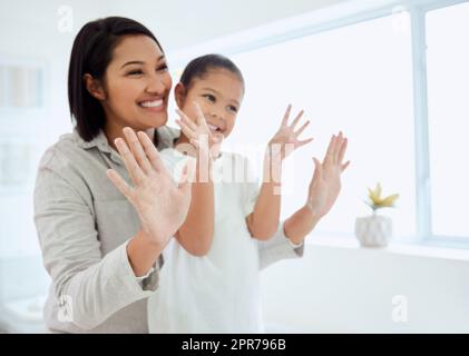 De bonnes habitudes d'hygiène commencent avec des mains propres. Photo d'une adorable petite fille se lavant les mains pendant que sa mère aide à la maison. Banque D'Images