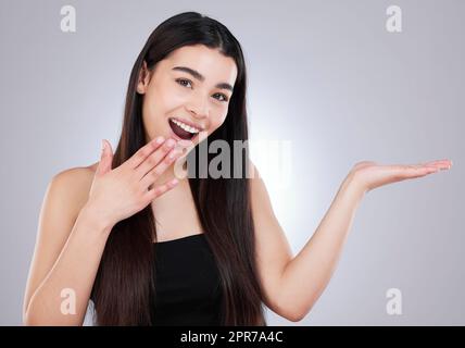 Avez-vous entendu parler de cela aussi. Studio tourné d'une jeune femme attrayante regardant surpris tout en pointant vers le copyspace contre un fond gris. Banque D'Images