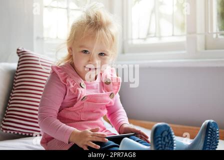 Je m'ai du temps. Une petite fille utilisant un téléphone à la maison. Banque D'Images