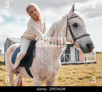 Personne ne peut enseigner l'équitation aussi bien qu'un cheval. Une jeune femme au-dessus d'un cheval sur une ferme. Banque D'Images