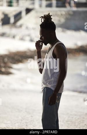 En roulant dans les rues avec Mary Jane. Un jeune homme qui fume une cigarette de marijuana sur un fond urbain. Banque D'Images