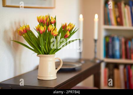 Bouquet de tulipes jaunes dans un vase comme décoration de salon ou pièce maîtresse symbolisant l'amour, l'affection ou le geste de soin. Bouquet de fleurs fraîchement coupées sur une table en bois dans une bibliothèque ou un bureau Banque D'Images