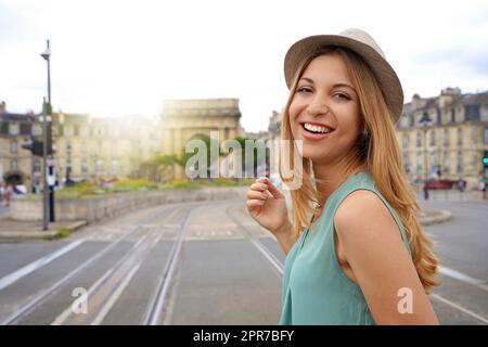 Portrait d'une jeune touriste souriante regarde la caméra sur le pont de pierre à Bordeaux, France Banque D'Images