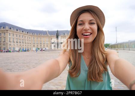 Selfie fille élégante à Bordeaux, France. Une jeune touriste prend son autoportrait à la place de la Bourse, Bordeaux, France. Banque D'Images