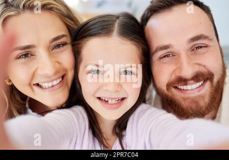 Gros plan d'adorable petite écolière prenant le selfie avec ses parents . Parents amoureux posant avec leur fille pour l'auto-portrait image. Banque D'Images