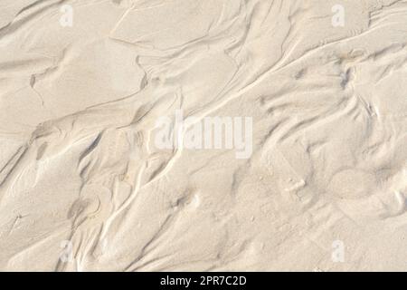 Résumé sable blanc sédiments modèle, littoral naturel bio paysage brillant au soleil. Vue de dessus d'une image texturée conceptuelle de sable marin humide formé au bord de la mer lors de vacances d'été. Banque D'Images