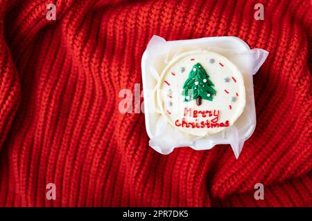 Gâteau de Noël avec l'inscription joyeux noël, décoré de glaçage, sur fond rouge, vue du dessus. Banque D'Images