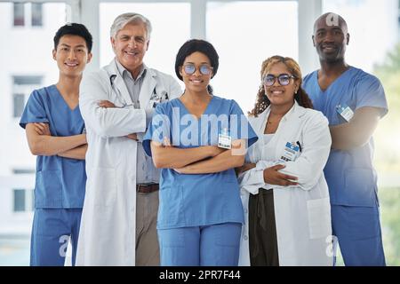 Nous sommes chacun compétents et avons une contribution vitale à partager. Portrait d'un groupe de médecins debout avec leurs bras croisés dans un hôpital. Banque D'Images