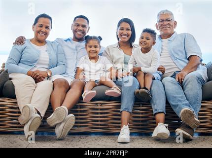 Heureux et content famille hispanique souriant tout en se relaxant et assis sur le canapé ensemble à la maison. Un petit frère et une sœur joyeux et insouciants qui apprécient le temps passé avec leurs parents et grands-parents Banque D'Images