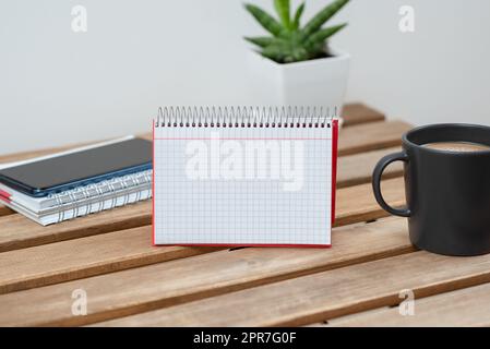 Écran du téléphone avec messages importants placés sur la table avec café, stylo, ordinateurs portables et usine. Des idées récentes sont présentées sur la tablette du bureau avec une tasse et une fleur. Banque D'Images