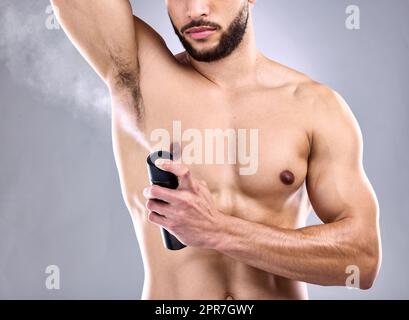 Je veux sentir bien. Studio photo d'un jeune homme pulvérisant déodorant sur son aisselle. Banque D'Images