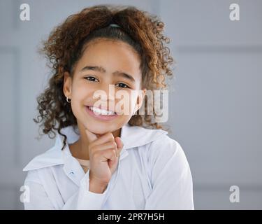 MMM... Je me demande. Portrait court d'une adorable petite fille debout avec sa main sur son menton et regardant réfléchie. Banque D'Images