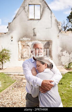 Perdre votre maison est comme perdre un morceau de votre coeur. Un couple senior se réconfortant après avoir perdu leur maison à un feu. Banque D'Images