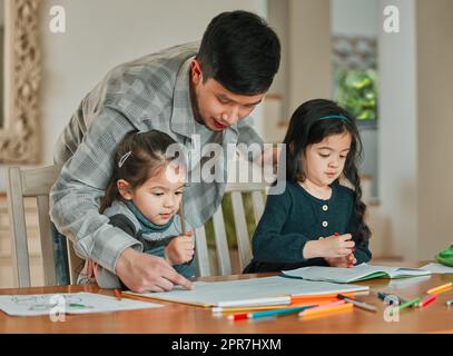 Yourre tous deux si talentueux. Un jeune père qui aide ses filles à faire leurs devoirs. Banque D'Images