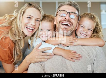 Portrait d'une famille de quatre personnes de race blanche se détendant dans le salon à la maison. Famille souriante affectueuse ensemble. Jeunes couples se liant avec leurs petits enfants à la maison Banque D'Images